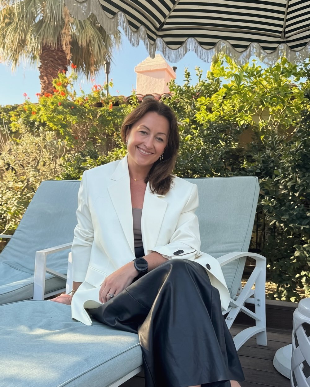 Cathy Cousins in a white blazer, smiling, seated outdoors
